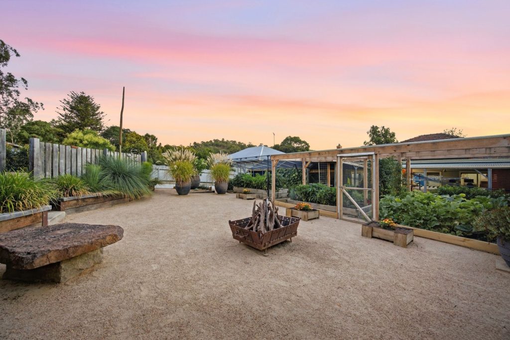Landscaped backyard with fire pit and productive vegetable gardens.