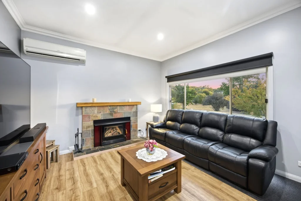 Comfortable living room featuring a wood fireplace and large window.